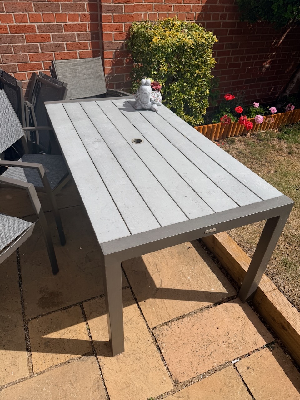 Grey garden table on a sunny patio, used as a practical outdoor work surface