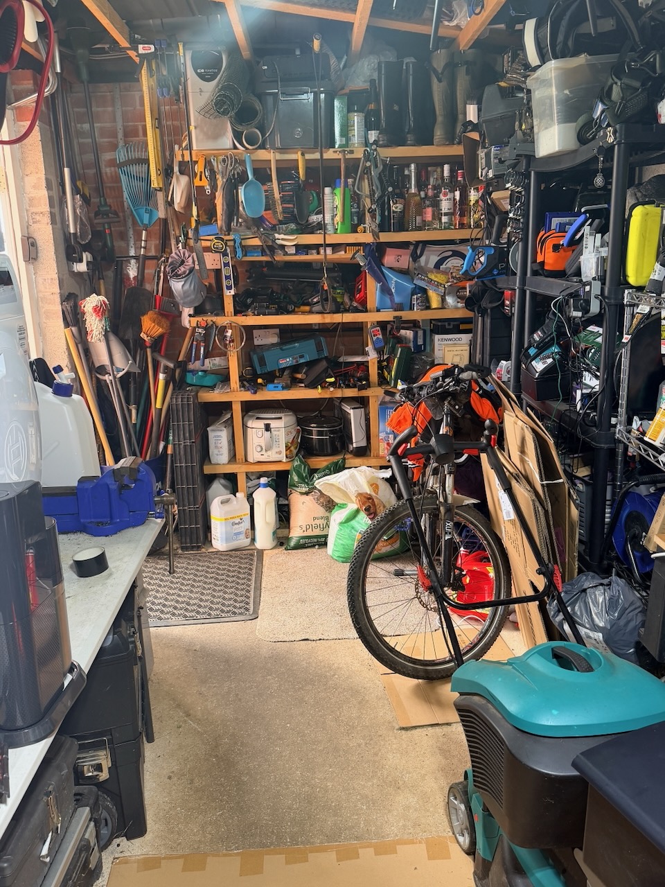 A crowded home garage with tools, equipment and a narrow working space